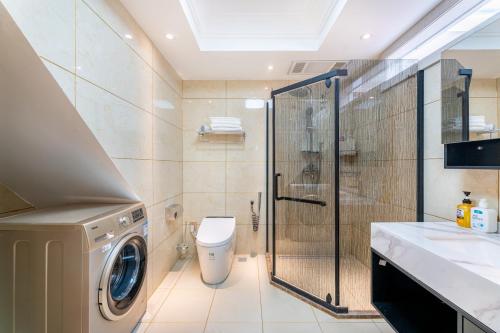 ein Bad mit einer Waschmaschine und einer Dusche in der Unterkunft Fancy Apartment in Suizhong