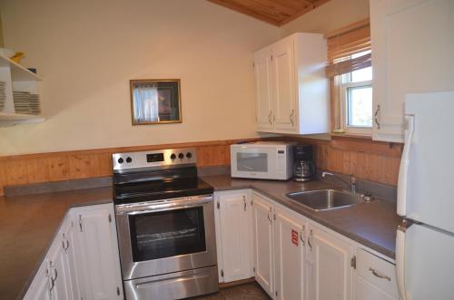 a kitchen with a stove and a sink and a refrigerator at Sundance Cottages in Cavendish