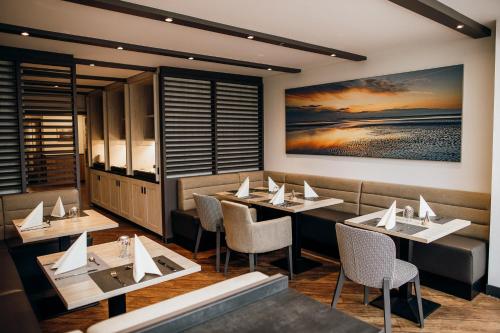 a restaurant with tables and chairs and a painting on the wall at Landgasthof "Zum grünen Walde" in Nordholz