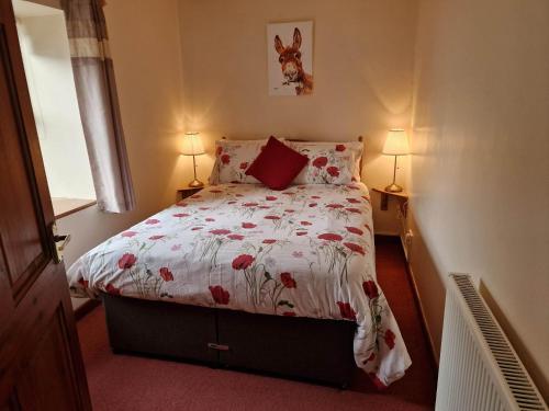 a small bedroom with a bed with a floral comforter at Ddol Cottage Traditional Coastal cottage nr Llangrannog & New Quay with Donkeys in Llandysul