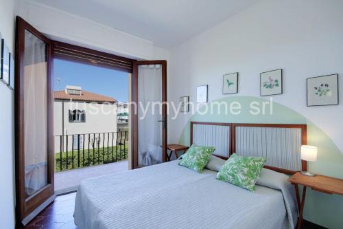 une chambre avec un lit et une grande fenêtre dans l'établissement Vela, terrazza sul mare, 2 camere, clima e posto auto a soli 50 m dal mare! by Alfareal, à Castiglione della Pescaia