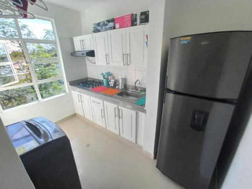 a kitchen with a black refrigerator and white cabinets at Studio In Novalito Neighborhood in Valledupar