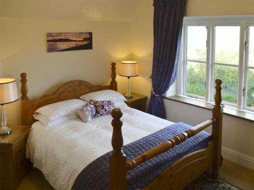 a bedroom with a bed and two windows at The Headmasters Cottage in South Hill