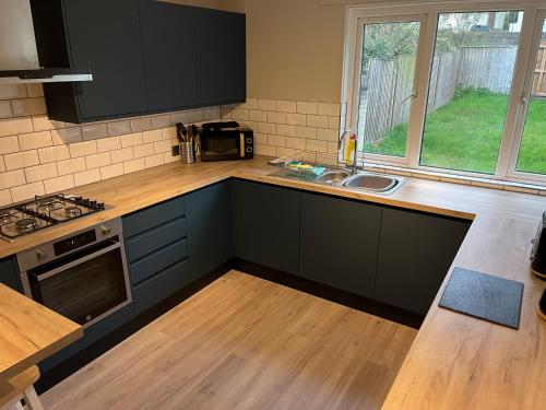 a kitchen with black cabinets and a sink and a window at 5 Bed Camberley Airport Accommodation in Camberley