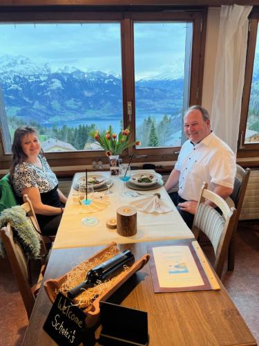 a man and woman sitting at a table in a restaurant at Hotel Fassbind Beausite in Beatenberg