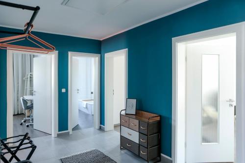 a room with blue walls and a room with a dresser at Lumen Homes - Design-Apt. nahe Audi und Altstadt, 3 Zimmer, NETFLIX in Ingolstadt
