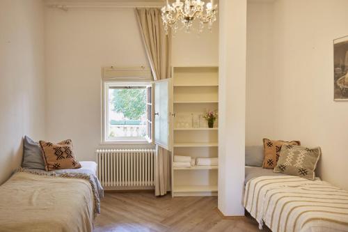 a bedroom with two beds and a window and a chandelier at Schloss Mörlbach in Icking