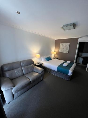 a hotel room with a bed and a couch at Pevensey Motor Lodge in Echuca