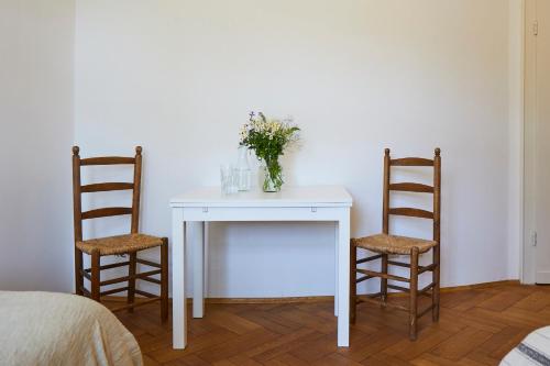 a white table with two chairs and a vase of flowers at Schloss Mörlbach in Icking