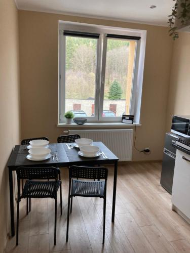 comedor con mesa, sillas y ventana en Apartament Górski, en Szczytna