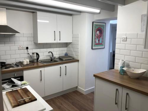 a kitchen with white cabinets and a counter top at SEREN cottage by the sea in Llangadwaladr