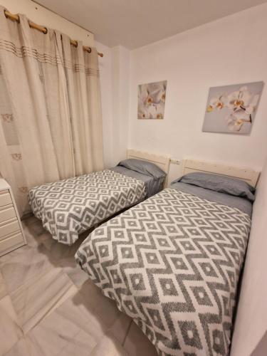 two twin beds in a room with curtains at Apartamento playa - Puerto Banus in Marbella