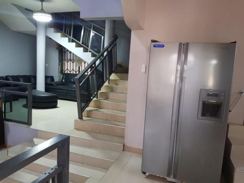 a stainless steel refrigerator in a room with stairs at Queen's Hill Lodge in Oblogo