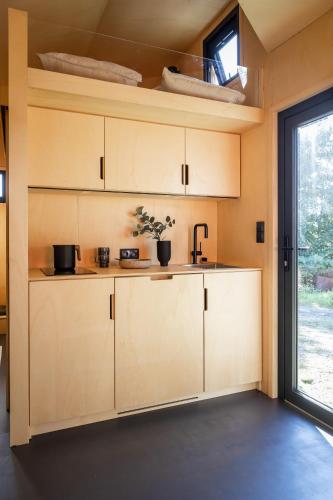 a kitchen with white cabinets and a window at Tiny House in the countryside in Årnes