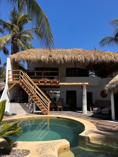 ein Resort mit einem Pool und einem strohgedeckten Gebäude in der Unterkunft Villa Bamboo in Coyuca