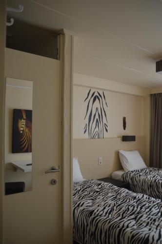 a bedroom with two beds and a zebra painting on the wall at B&B The Protea in Zonnebeke