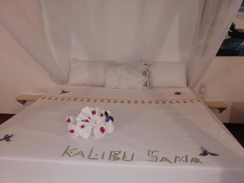 a bedroom with two beds with white sheets and flowers at Babalao Rooftop Hotel in Paje