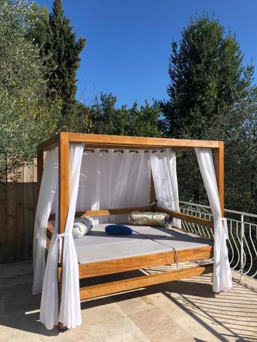 - un lit à baldaquin avec un rideau blanc sur la terrasse dans l'établissement villa la source claire, à Carros