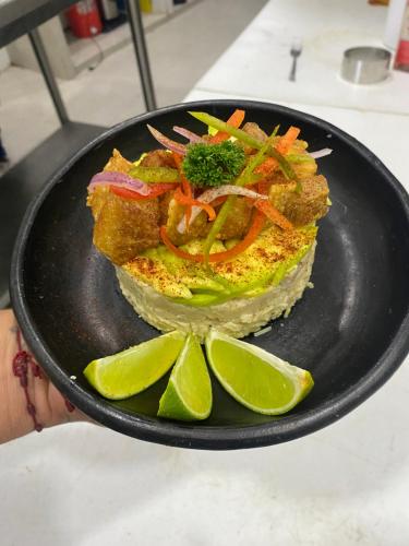 a plate of food with a sandwich with vegetables and lime slices at Apartahotel Plaza de ángel 74 in Barranquilla