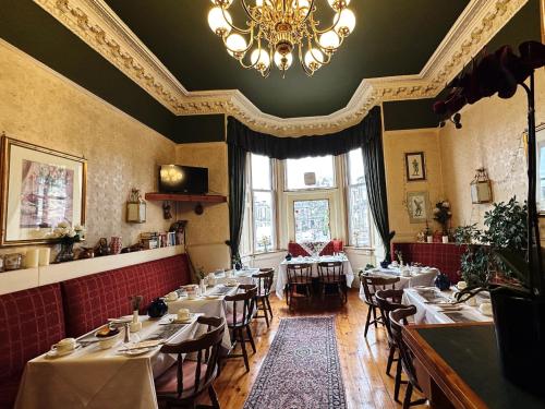 a restaurant with tables and chairs and a chandelier at Rosehall Hotel in Edinburgh