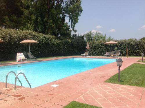 a swimming pool with two chairs and umbrellas at Le case di Anita in Toscana -Capalbio in Capalbio