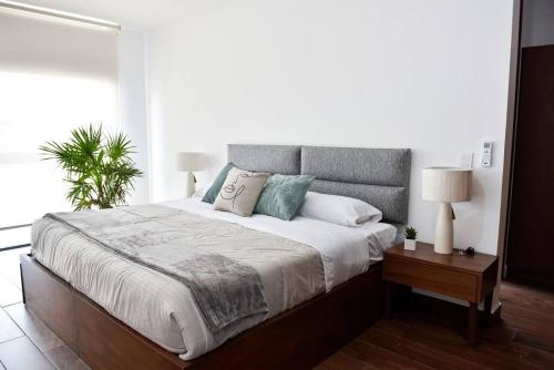 1 dormitorio con 1 cama grande con sábanas blancas y almohadas azules en Casa con Vista al Cielo en Aguascalientes