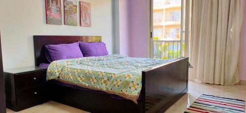 沙姆沙伊赫的住宿－Chillax The View Resort，一间卧室配有一张带紫色枕头的床和窗户。