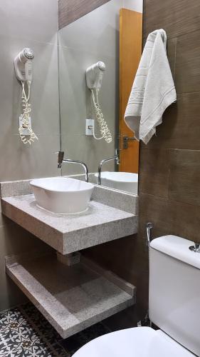 a bathroom with a sink and a toilet and a mirror at Hotel Rio in Guarujá