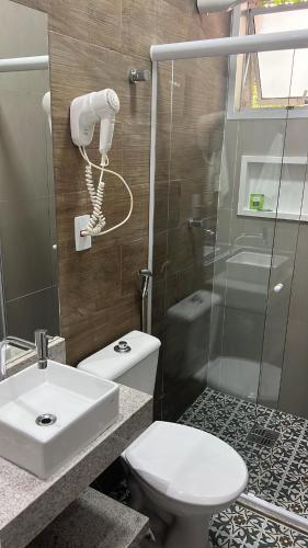 a bathroom with a toilet and a sink and a shower at Hotel Rio in Guarujá