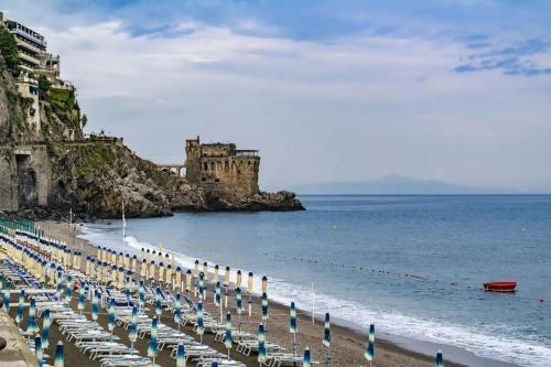 una playa con sillas y sombrillas y un castillo en Zagara Bianca, en Maiori