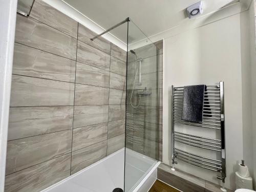 a shower with a glass door in a bathroom at Pomelo Tree Apartment in Cambridge