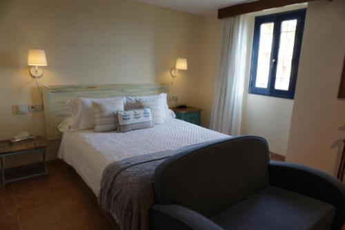 a bedroom with a bed with a chair and a window at Hotel Sant Joan in Palamós