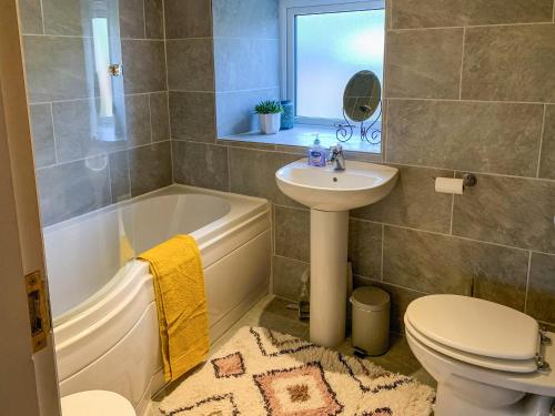 a bathroom with a sink and a tub and a toilet at Primrose Cottage in Winewall