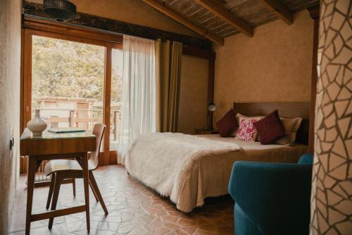 a bedroom with a bed and a desk and a window at El EQUIMITE HOTEL BOUTIQUE in Coatepec