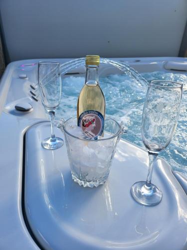 Una botella de vino en una bañera con dos copas de vino en Thermae D'Olimpia & SPA - Adults Only 14 Plus, en Băile Herculane