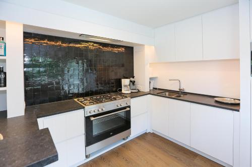 une cuisine avec des armoires blanches et un four à plaques de cuisson dans l'établissement Casa Dunas, à Middelkerke