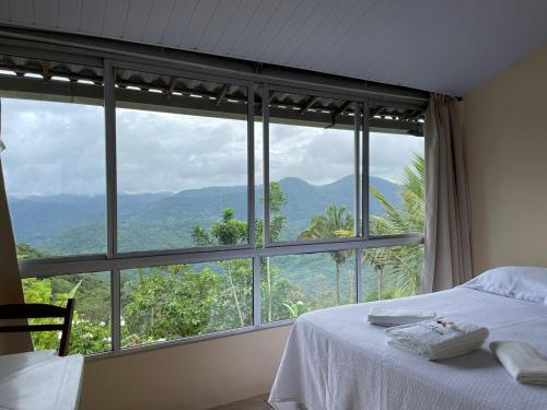 a bedroom with a bed and a large window at Chacara da Sorte in Pacoti