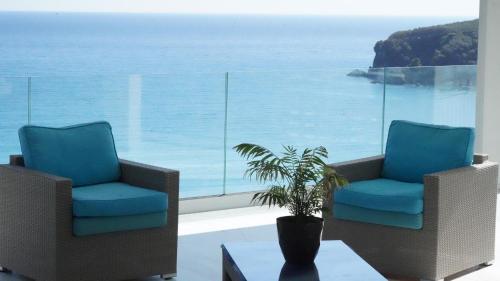 two chairs and a potted plant in front of a window at Valtos View in Parga