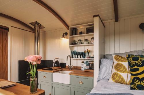 a kitchen with a sink and a couch in a room at Luxury Shepherd's Hut on Flower Farm with Outdoor Bath in Mid Cornwall in Truro