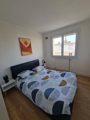 ein Schlafzimmer mit einem Bett mit einer Bettdecke und einem Fenster in der Unterkunft T2 rénové avec parking gratuit sur place in Valence