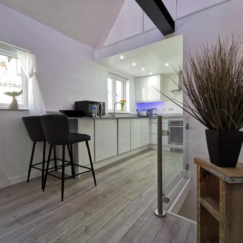 a kitchen with white cabinets and a table and chairs at AnchorageWells Lodge, Seaview Apartment in Wells next the Sea