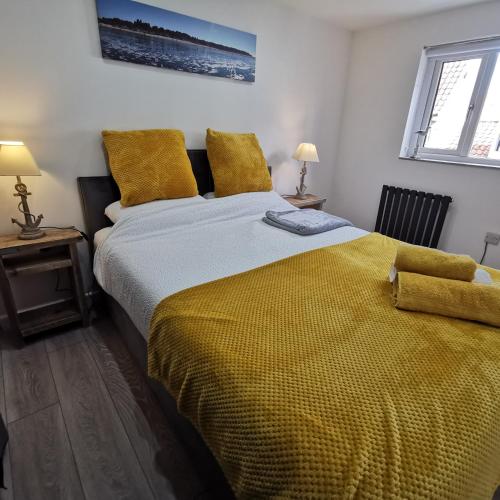 a bedroom with a large bed with a yellow blanket at AnchorageWells Lodge, Seaview Apartment in Wells next the Sea