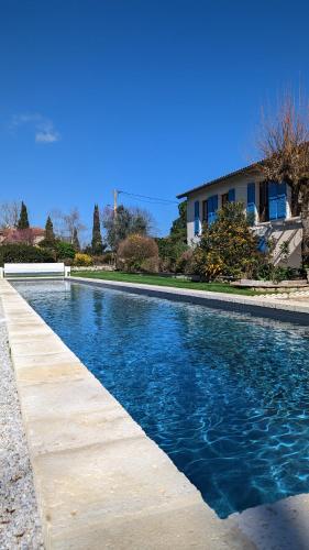 une piscine avec de l'eau bleue devant une maison dans l'établissement La Maison des Eaux, à Saint-Jean-de-Thurac