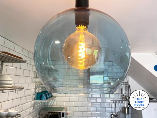 a glass light hanging from a ceiling in a kitchen at Welcome to The Light House a tranquil city retreat. in Southampton