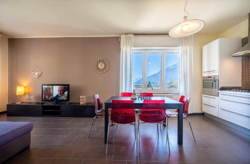 uma sala de estar com uma mesa de jantar e cadeiras vermelhas em Lake view apartment with parking in Dongo - Larihome A26 em Dongo