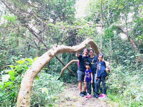 a family poses for a picture in front of a tree at Gibbon Singing Home Stay in Quan Tom