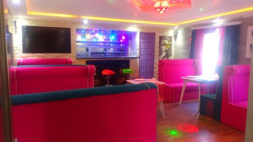 a room with pink chairs and a bar with a tv at Hotel Lilo near Airport in Tbilisi City