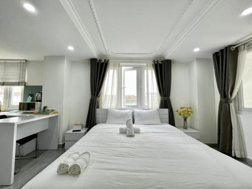 a bedroom with a large white bed with slippers on it at MơMơ Residence in Ho Chi Minh City