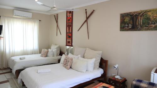 Habitación de hotel con 2 camas y almohadas blancas en Guest House Bavaria en Rundu
