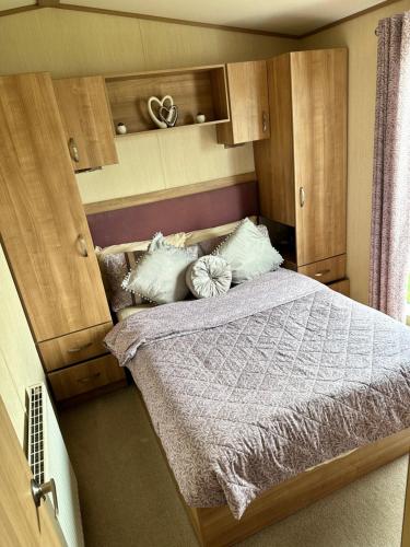 a bedroom with a large bed with wooden cabinets at Hot tub breaks Fairways Tattershall lakes in Tattershall